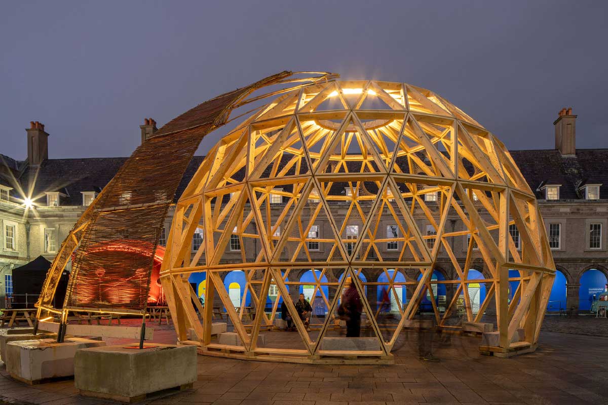 Wooden geodesic dome structure illuminated at night in the courtyard of the Irish Museum of Modern Art (IMMA).